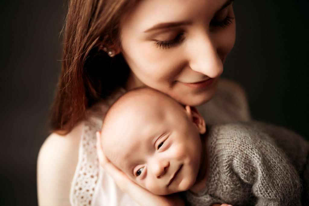 newborn cuddling with mom in a studio with a black backdrop